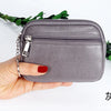 A hand holds a gray PU leather mini wallet with a silver keychain, shown against a white background.