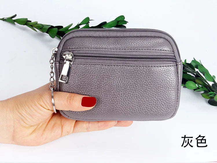 A hand holds a gray PU leather mini wallet with a silver keychain, shown against a white background.