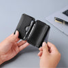 A hand holds a black magnetic foldable ID card holder and coin purse against a gray background.