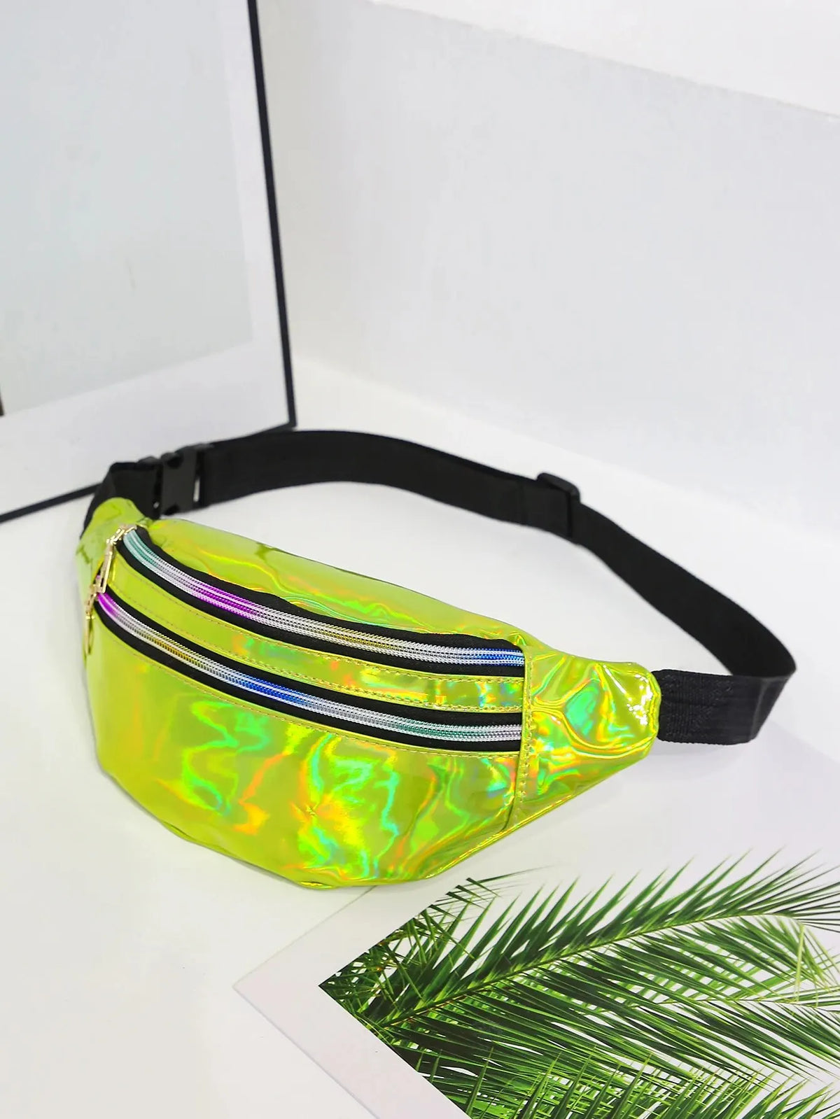 A neon yellow holographic sequin waist bag with a black adjustable strap resting on a white surface.