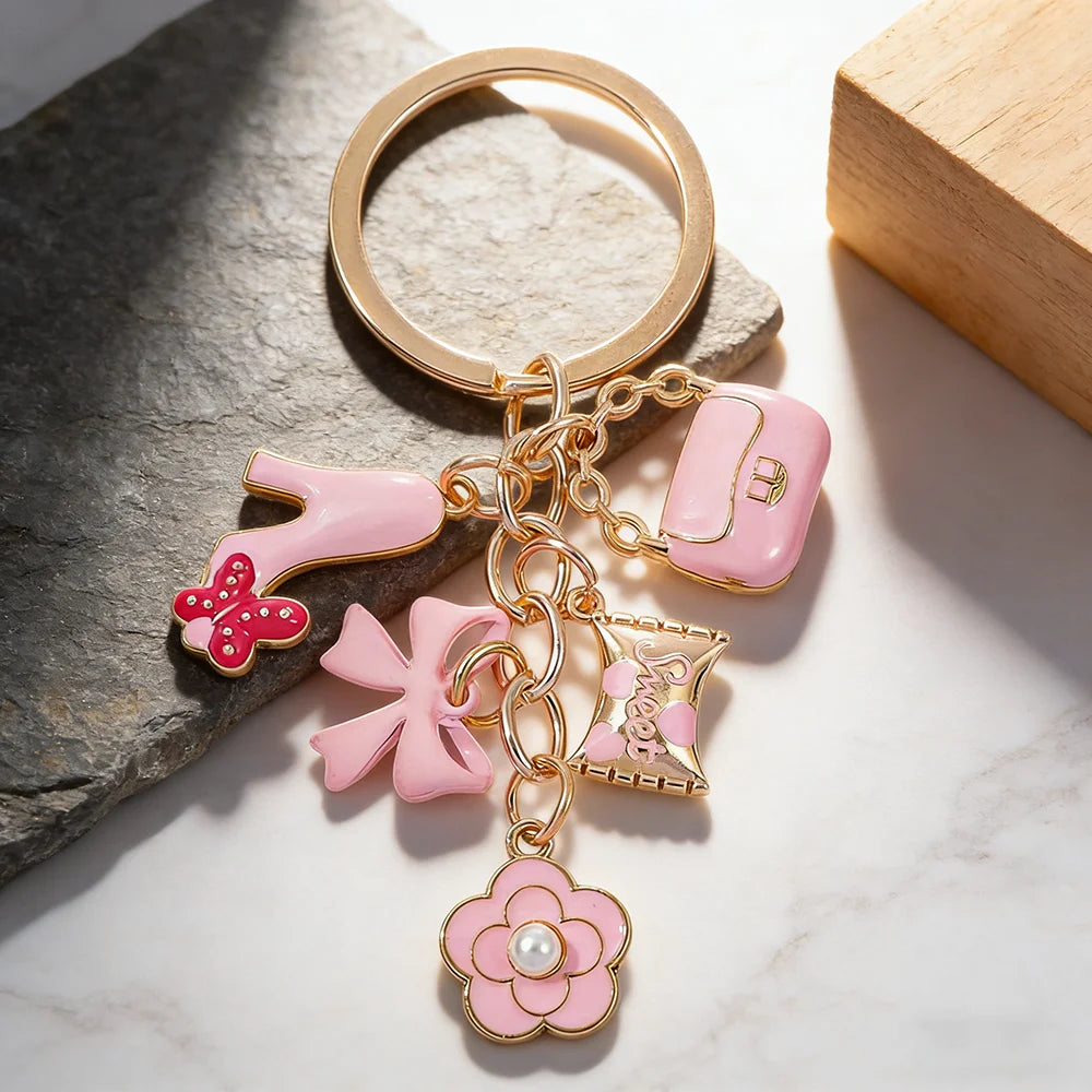 Clé-clés ton or avec des charms cœur, fleur et nœud rose sur une surface de pierre.