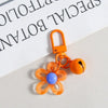 An orange resin flower keychain with a small lock and a yellow-orange bee charm.