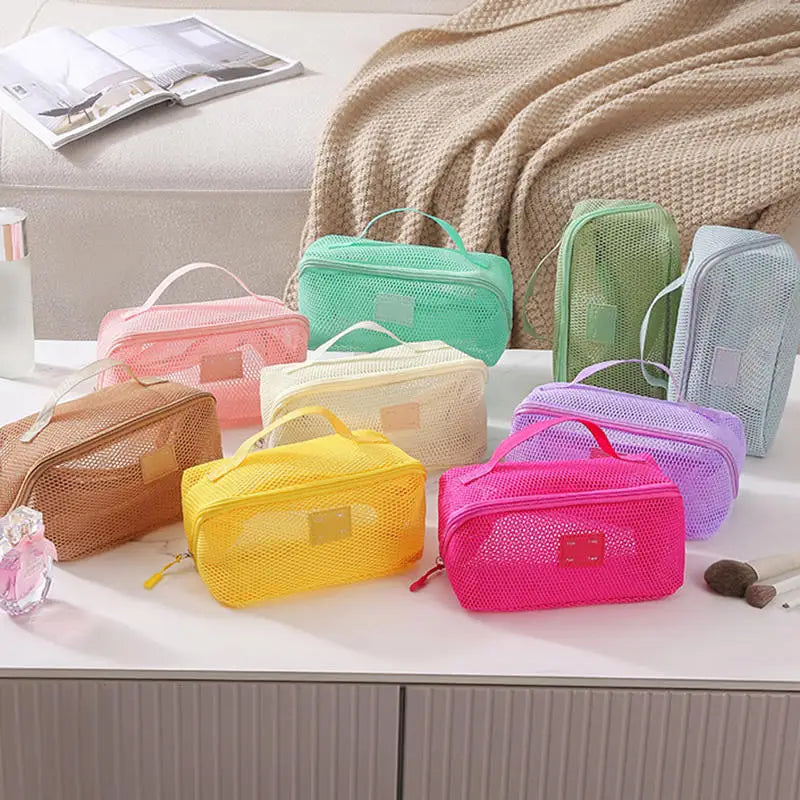 A collection of colorful mesh cosmetic organizer pouches in shades of pink, green, yellow, and lavender are displayed on a wh