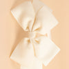 A set of twenty cream-colored ribbed fabric bow hairbands laid flat on a light beige background.