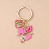 Gold-toned enamel keychain featuring a pink heart, a pink P, and a pink leaf design.