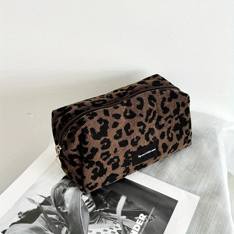 A brown and black leopard print makeup organizer bag resting on a white surface.