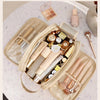A beige PU leather travel makeup organizer with double zippers filled with various cosmetic products and tools.