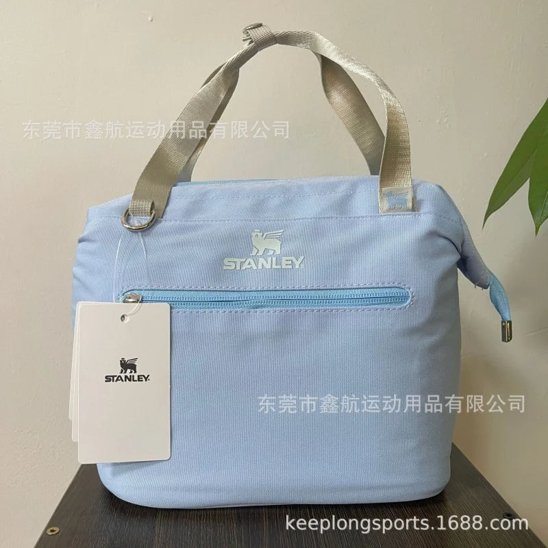 Light blue insulated cooler lunch bag with a gray strap and Stanley logo tag