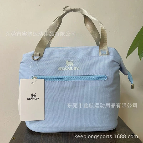 Light blue insulated cooler lunch bag with a gray strap and Stanley logo tag