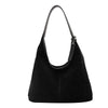 A black suede slouchy shoulder bag hanging from a thin strap.
