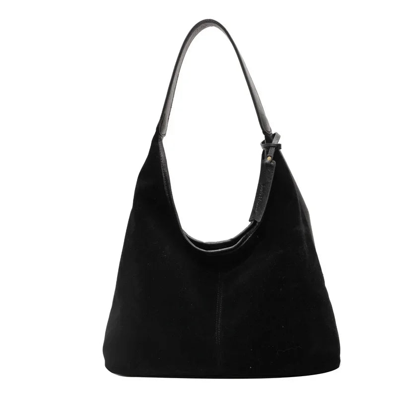 A black suede slouchy shoulder bag hanging from a thin strap.