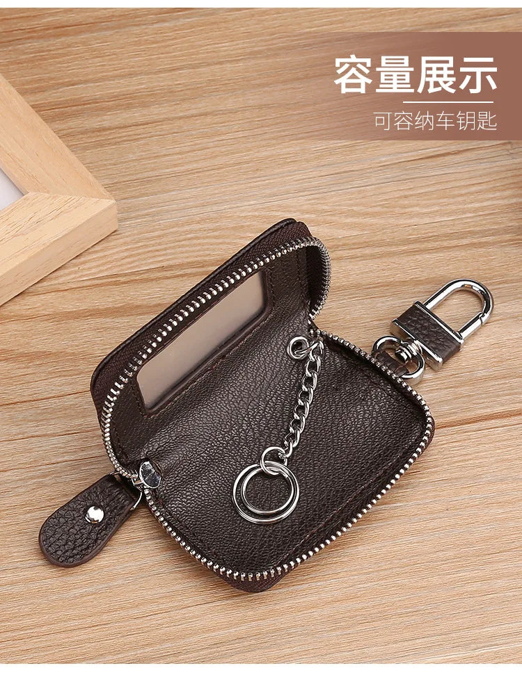 A dark brown leather car key case with a transparent window and silver chain attached, shown on a wooden surface.