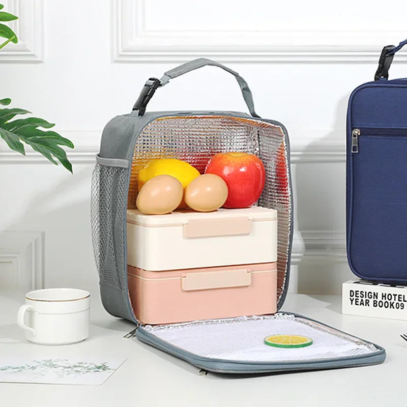 Grauer isolierter Lunchbeutel mit klarem Netzfenster, der Eier und einen Apfel enthält, auf weißem Untergrund.