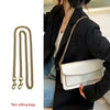 A woman holds a white quilted handbag with a gold metal chain strap under a black coat.