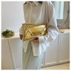 A woman holds a gold crocodile pattern coin purse clutch in front of a white cabinet and mirror.