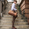 Junger Mann mit Kappe und Hemd geht die Treppe hinunter und trägt eine Vintage-Ledertasche.