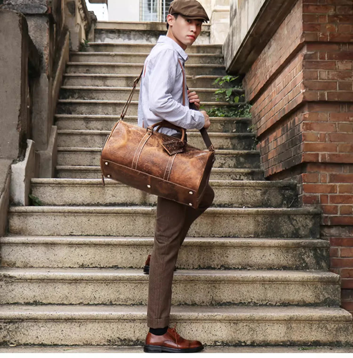 Junger Mann mit Kappe und Hemd geht die Treppe hinunter und trägt eine Vintage-Ledertasche.