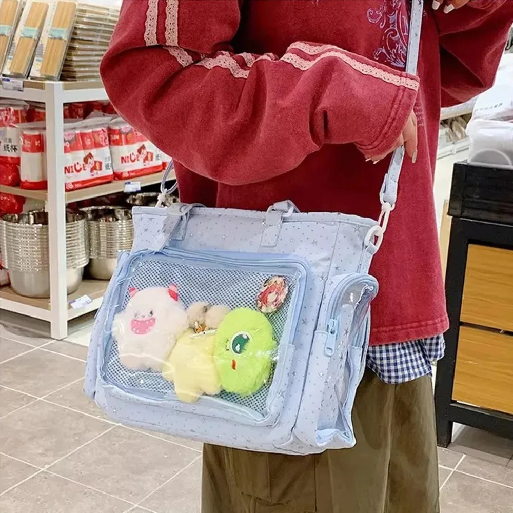 A person holds a light blue transparent shoulder tote bag filled with cute, soft toys in a retail setting.