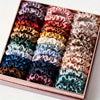 A box filled with 19 pieces of thin scrunchies hair ties in a variety of mixed satin colors.