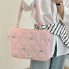Bolso de portátil acolchado rosa con lazo azul claro, sostenido por una persona con camisa blanca a rayas