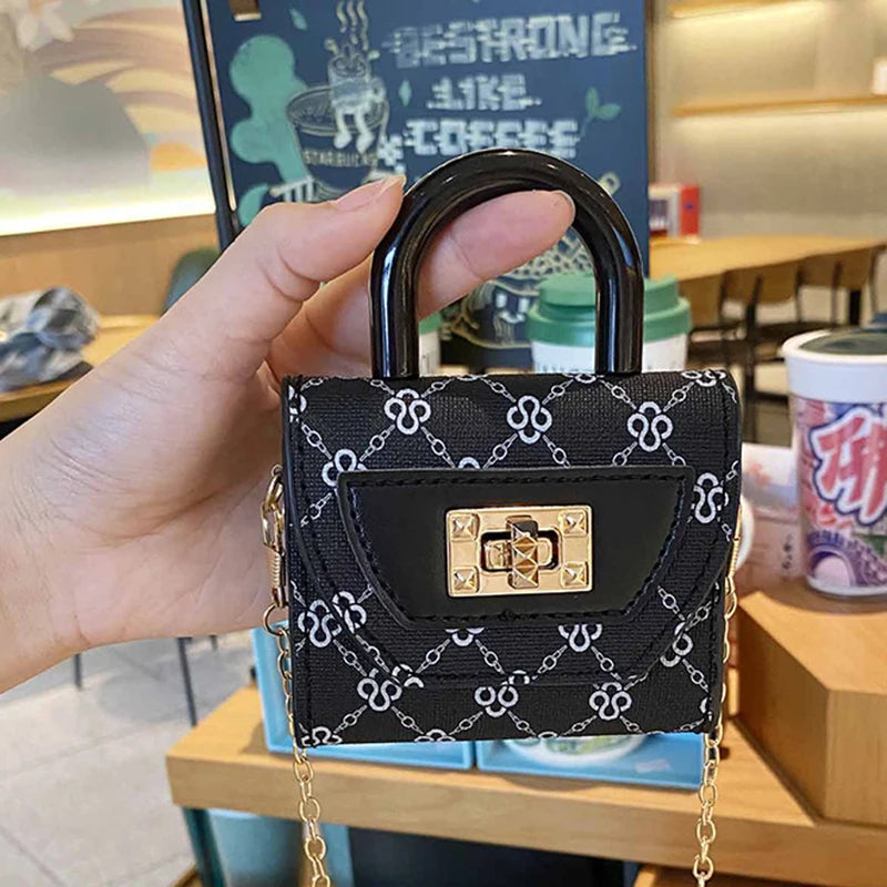 Bolso cruz floral negro texturizado con candado y cadena dorada, sostenido en una mano.