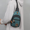 A person wearing a gray hoodie is holding an olive green nylon chest bag with black straps.
