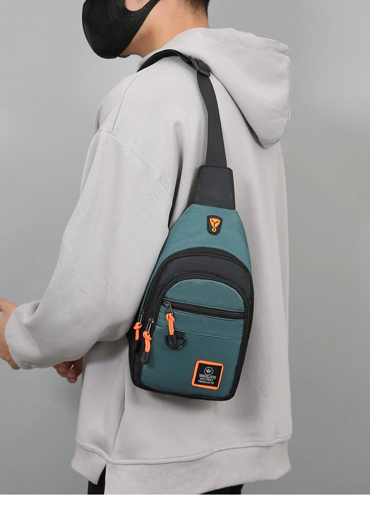 A person wearing a gray hoodie is holding an olive green nylon chest bag with black straps.