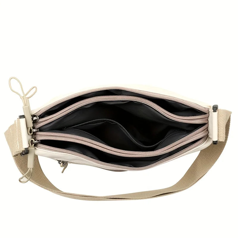 A beige nylon crossbody shoulder bag with multiple zippered compartments shown from the front.