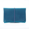 A teal minimalist full-grain leather passport holder and card wallet with a stitched closure.