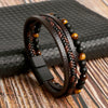 A stack of multi-layer brown leather bracelets featuring tiger eye and black beads on a wooden surface.