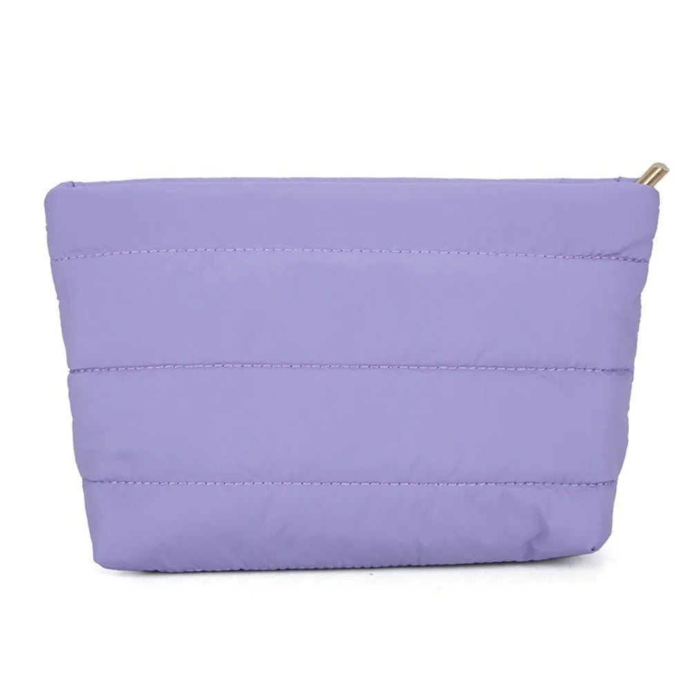 A lavender quilted cosmetic travel bag with a zipper closure.