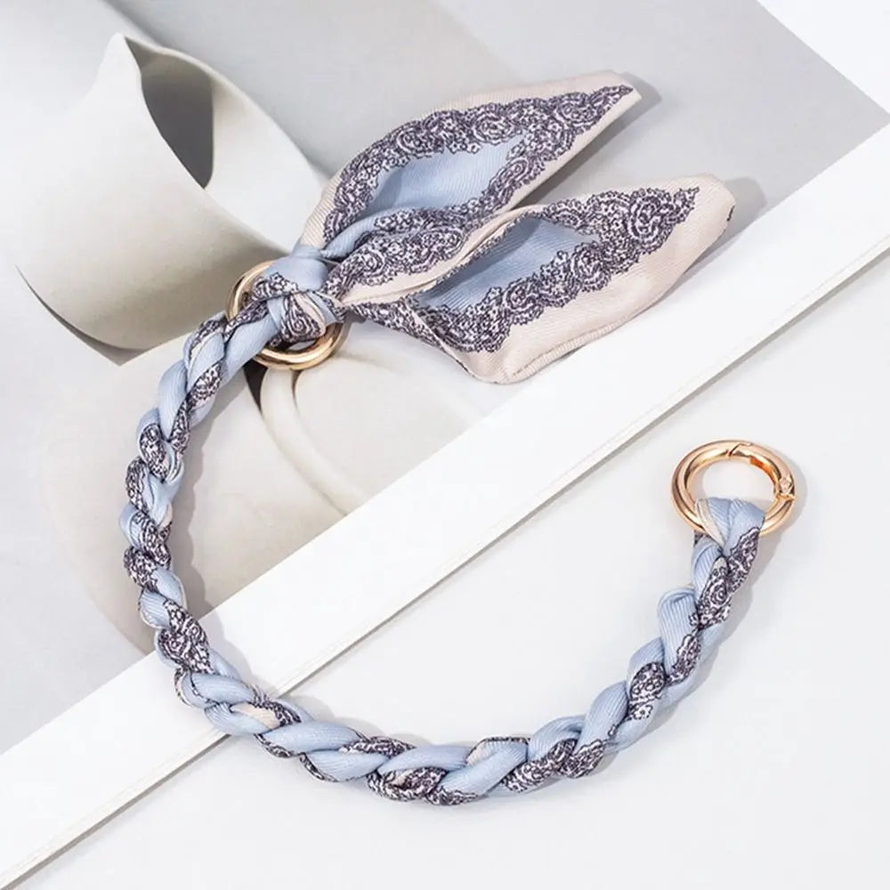 Zarte silber-blaue gemusterte Seidenschal-Taschenkette vor weißem Hintergrund