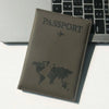 A brown leather passport holder with a world map design rests on a white surface next to a laptop keyboard.