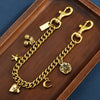 Gold alloy necklace featuring a chain and a cherry flower bag pendant displayed on a wooden tray.