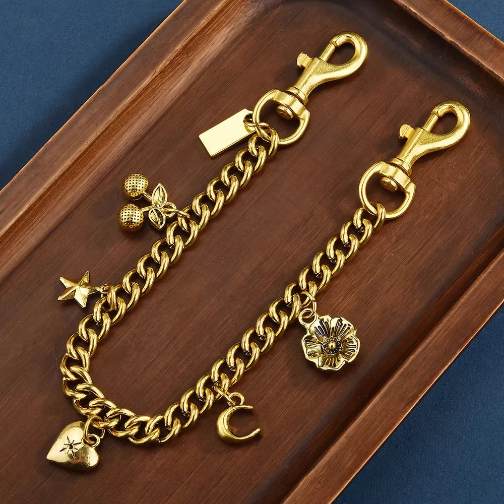 Gold alloy necklace featuring a chain and a cherry flower bag pendant displayed on a wooden tray.