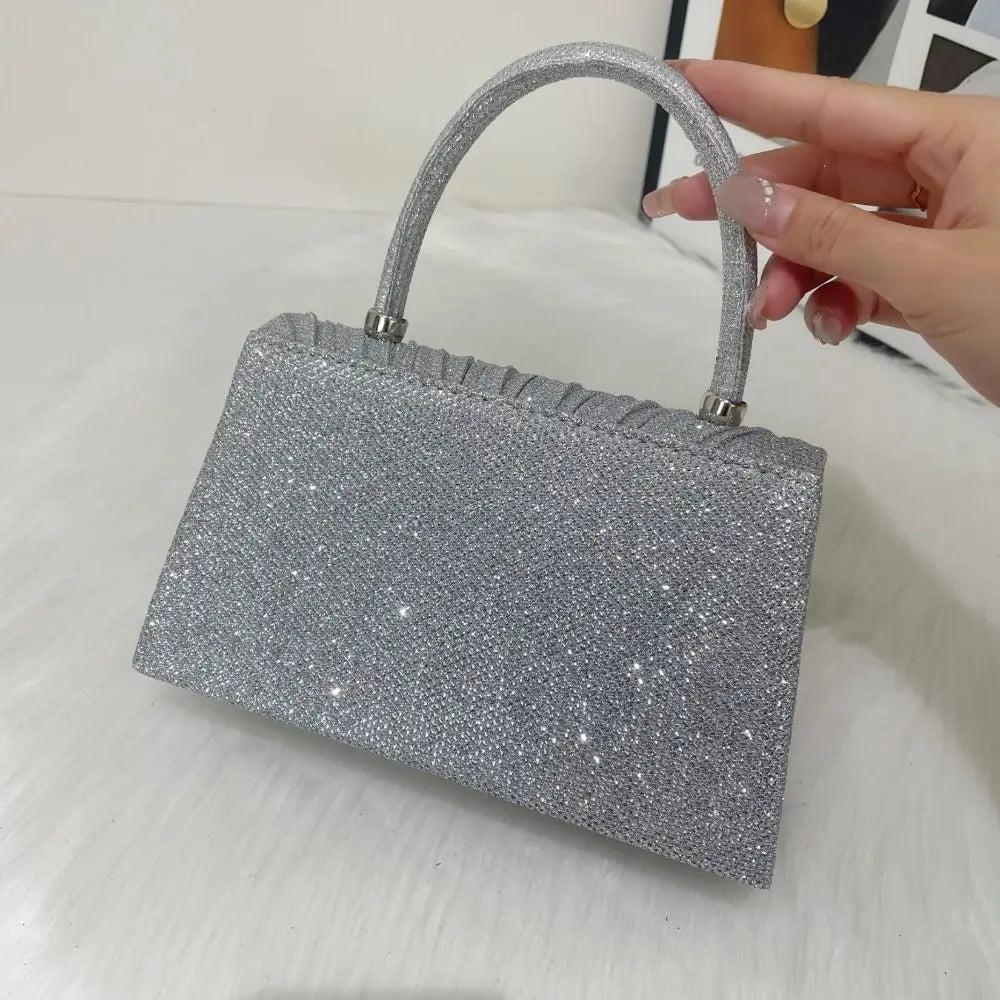 A silver glitter crossbody evening bag with a handle is shown against a white background.