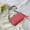 A pink multi-functional passport and document organizer bag lying on a white sheet with yellow tulips.
