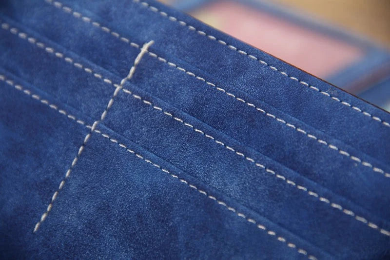 Close-up of a dark blue PU leather clutch wallet showing stitching and RFID protection details.
