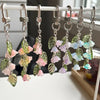 Handmade Lily of the Valley flower keychains with various shades of green and pink foliage hanging on a white rack.