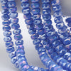 A close-up of blue iridescent AB faceted crystal glass beads shaped like wheels strung together for jewelry making