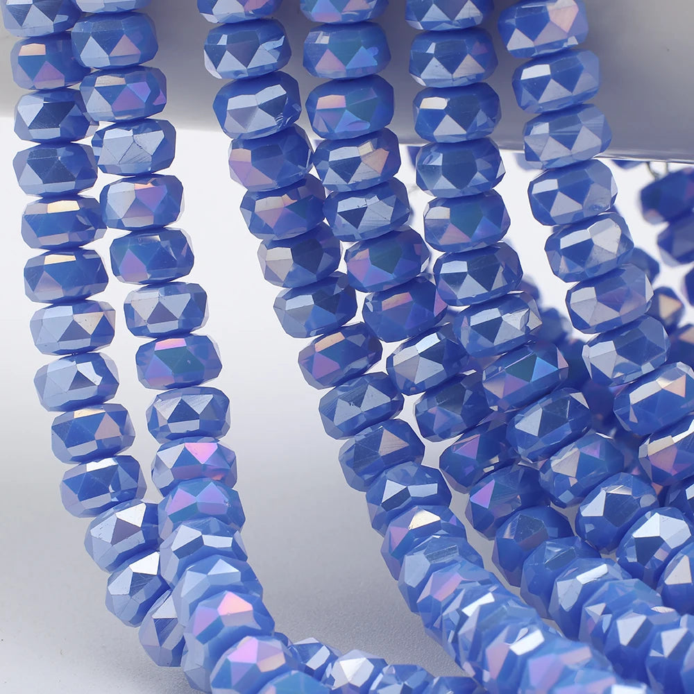 A close-up of blue iridescent AB faceted crystal glass beads shaped like wheels strung together for jewelry making