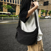 A woman wearing a black soft nylon crossbody shoulder bag while standing on an asphalt road.