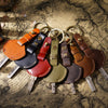 A collection of genuine leather key fob covers and keychains arranged on aged parchment paper.