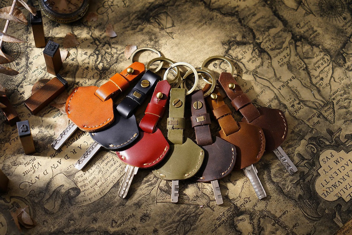 A collection of genuine leather key fob covers and keychains arranged on aged parchment paper.