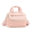 A light pink quilted mommy bag with a woven texture and a matching strap.