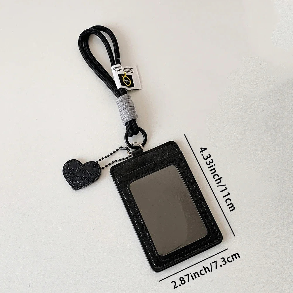 A black leather credit card and ID holder attached to a keychain with a heart charm.