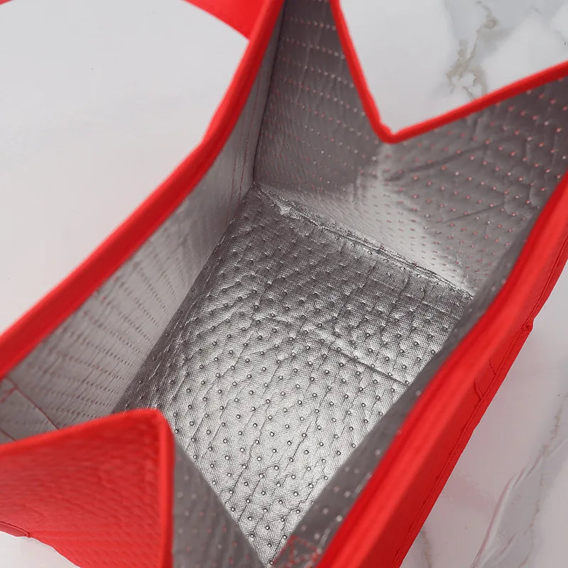 A close-up view of a red insulated tote bag with a silver aluminum lining.