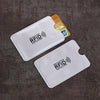 Two white anti-scan card sleeves for credit and RFID protection are shown on a dark surface.