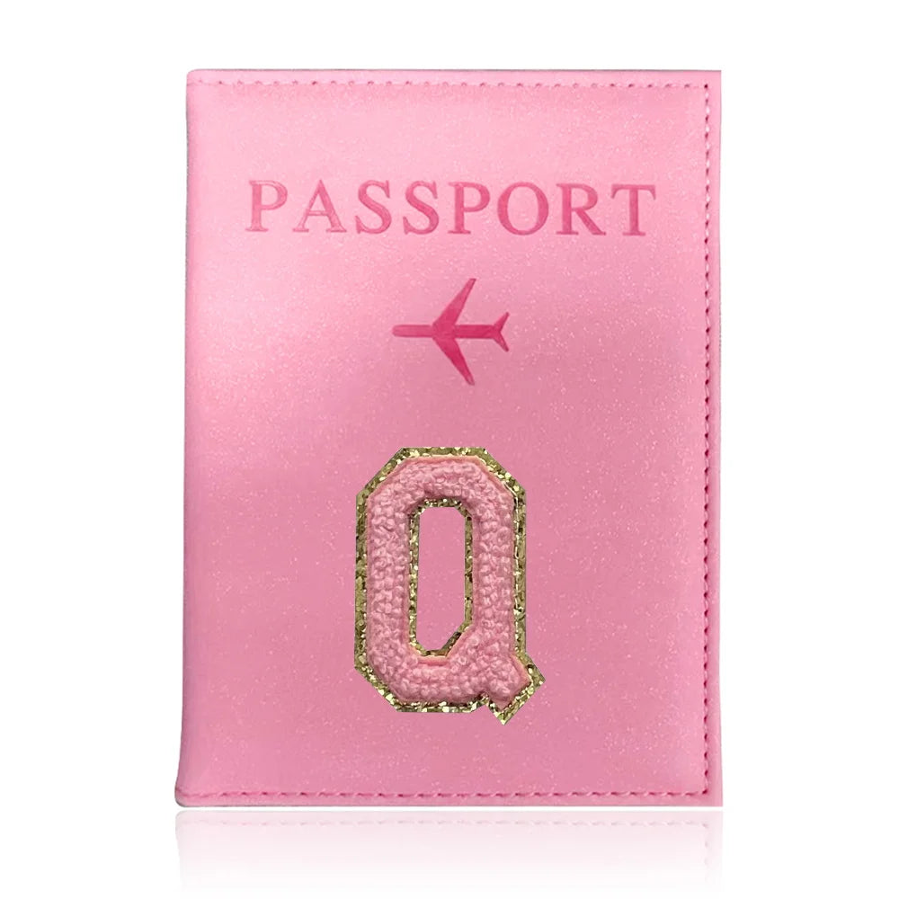 A pink leather passport holder with a stylized gold letter O and an airplane icon.