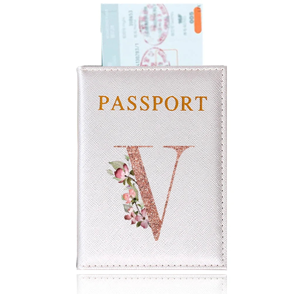 A pink leather passport holder with gold lettering and a rose gold initial design.